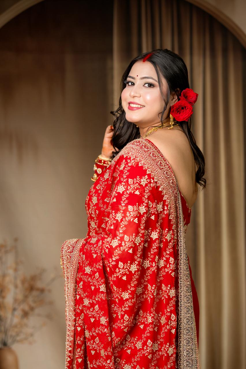 Woman in a red traditional outfit with gold details against a beige curtain background