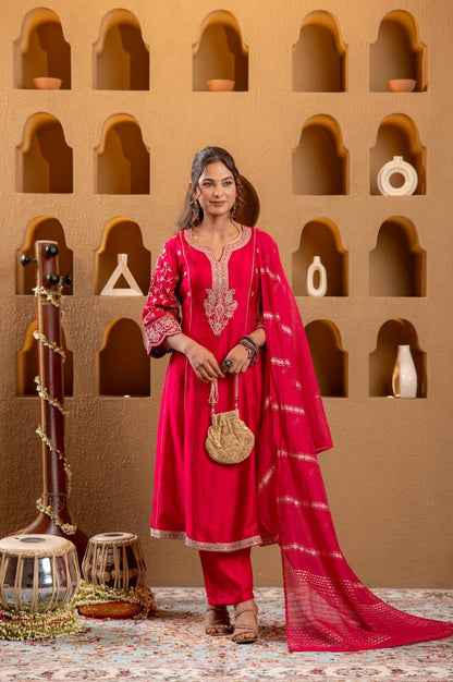 Woman standing in rani pink Viscose Silk kurta set with gold embroidery holding potli bag, niche wall backdrop - Jagranee