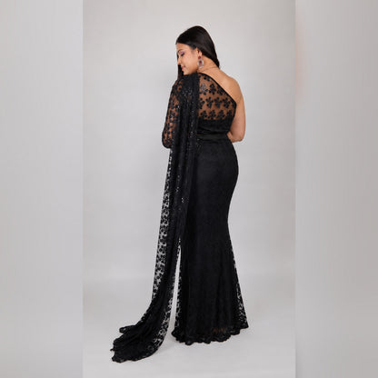 Back view of black sequin net mermaid saree gown showing sheer lace back, one-shoulder sleeve and pallu trail - Jagranee