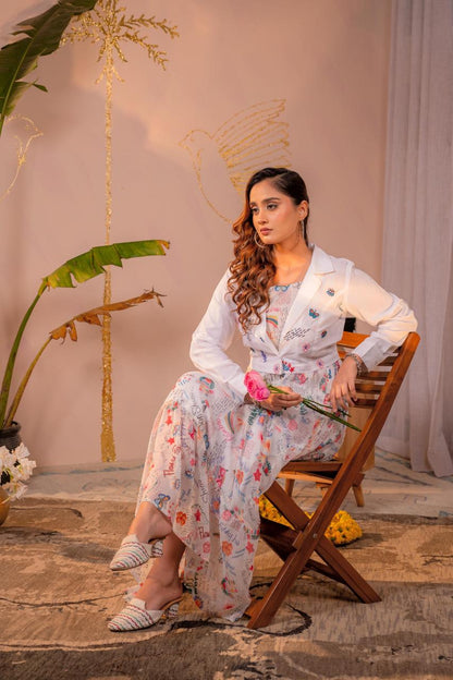 Seated full body view of white doodle art printed chiffon maxi dress with embroidered cropped blazer co-ord set - Jagranee