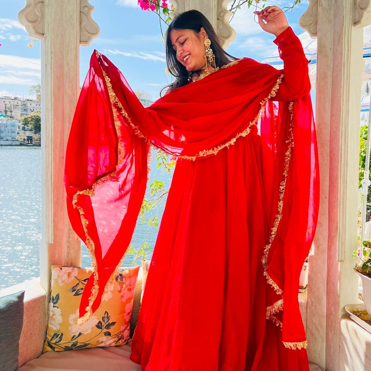 Twirling pose in red flowing georgette Anarkali gown with gold lace dupatta flying, white marble palace gazebo backdrop - Jagranee
