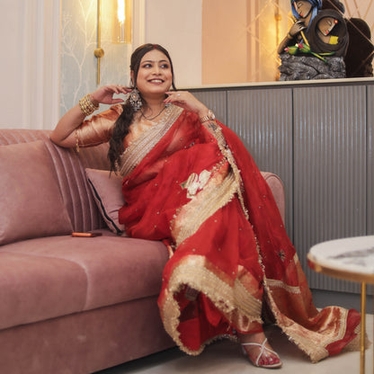 Seated pose in red tissue organza saree with scattered pearl work and gold lace fringe border, gold brocade blouse - Jagranee