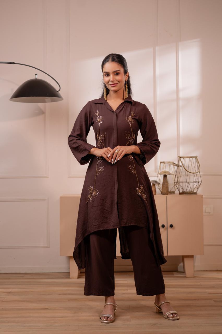 Woman wearing dark brown crepe high-low kurta set with gold sequin dandelion embroidery and wide-leg palazzo pants, front view - Jagranee
