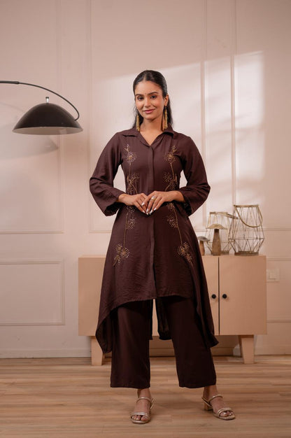 Woman wearing dark brown crepe high-low kurta set with gold sequin dandelion embroidery and wide-leg palazzo pants, front view - Jagranee