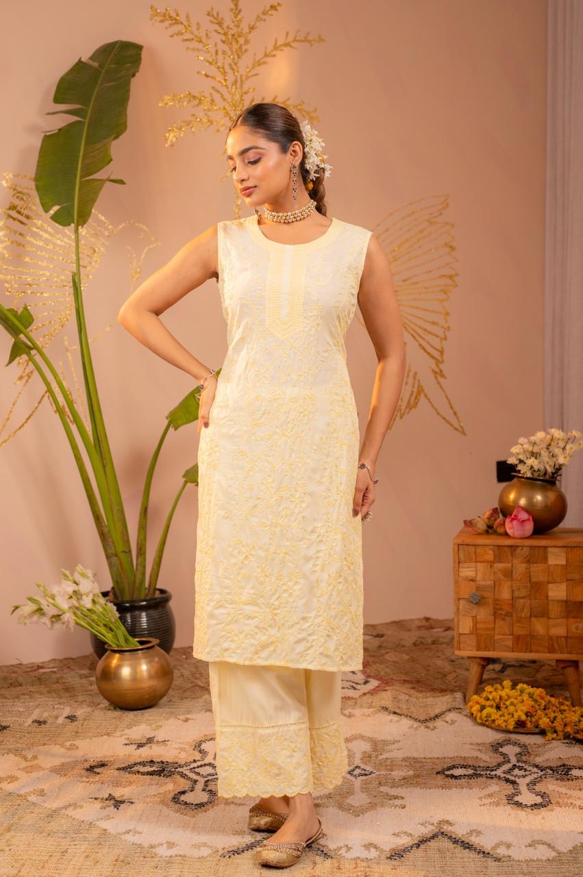Lifestyle pose in lemon yellow chikankari sleeveless kurta set with flowers in hair, full body - Jagranee