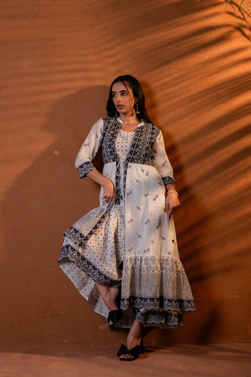 Leaning pose in black and white block print Anarkali dress showing jacket overlay and tiered skirt detail - Jagranee